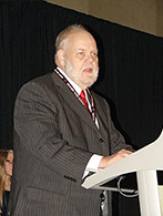 Dave Arneson delivering a talk from behind a white lecturn 2008