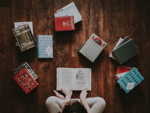 A person sitting, surrounded by books. 